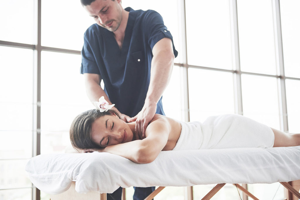 Femme couchée sur une table de massage et qui reçoit un massage